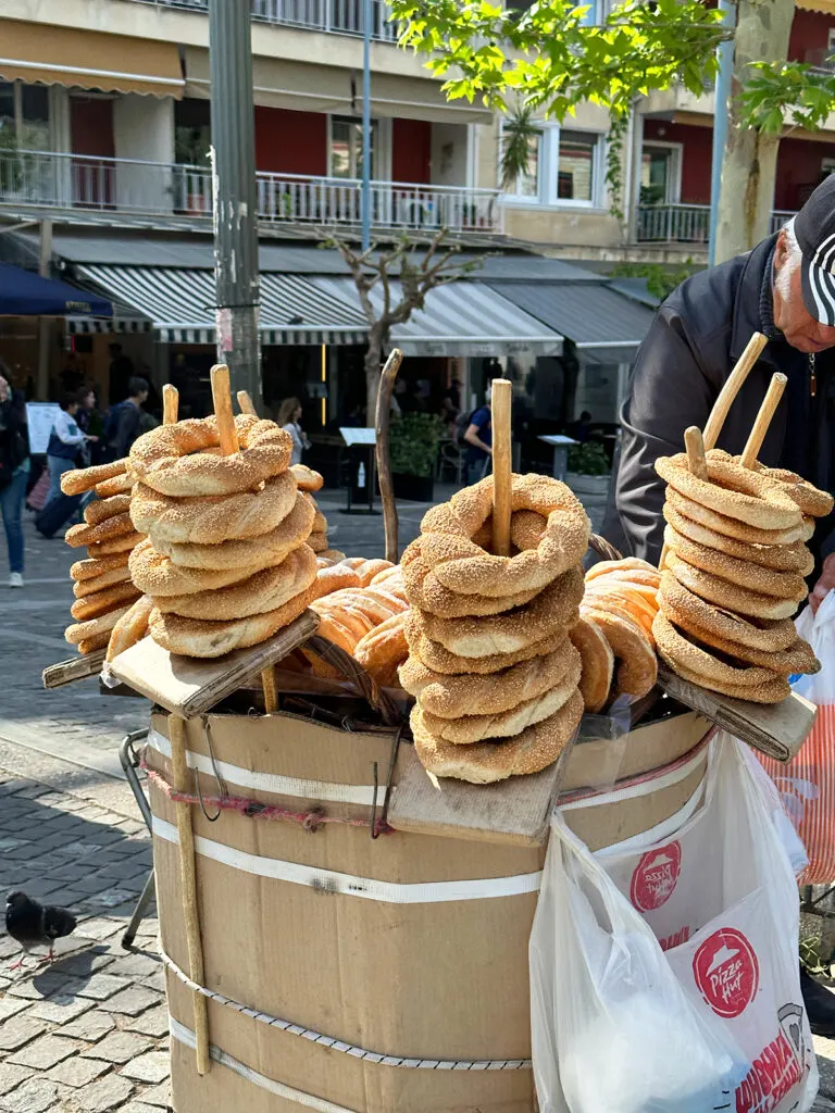 what to do in athens in 2 days view of street food large pretzels with seeds stacked on cart with building in distance