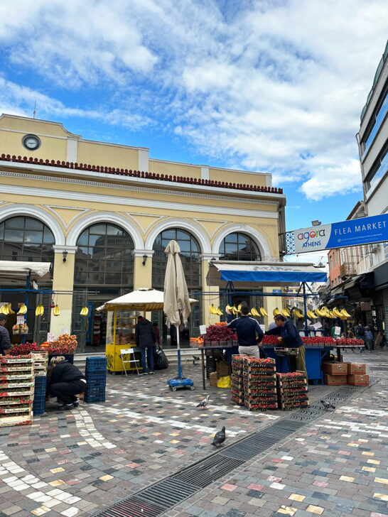 2 days in Athens Monastiraki square with vendors selling fruit in town square with yellow building behind