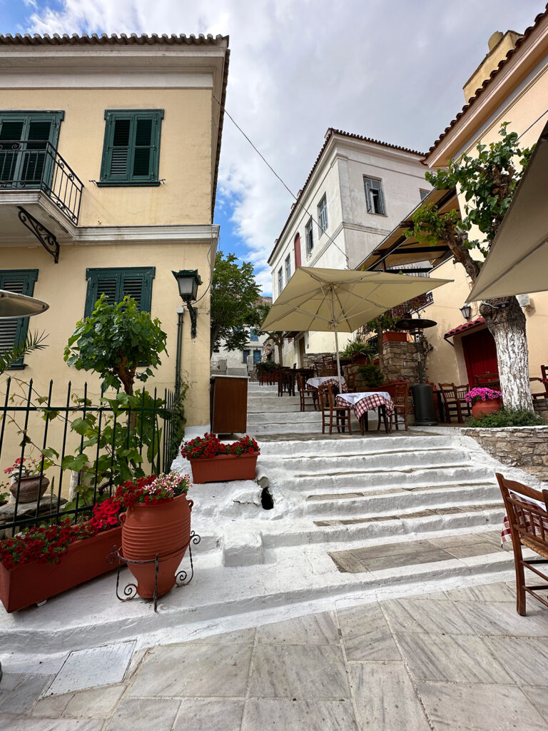 stone steps and beautiful buildings with cafe on alleyway in Greece