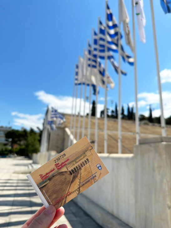 hand holding ticket with flags and stadium behind