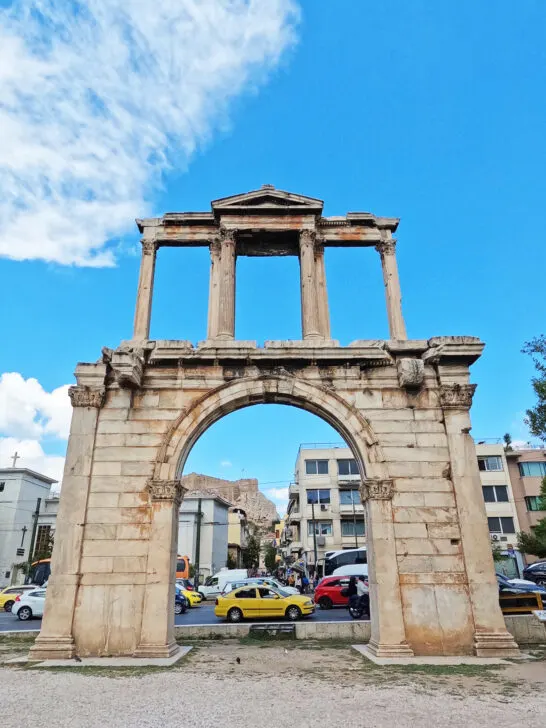 large stone arch with two layers and showing signs of disrepair with busy street behind