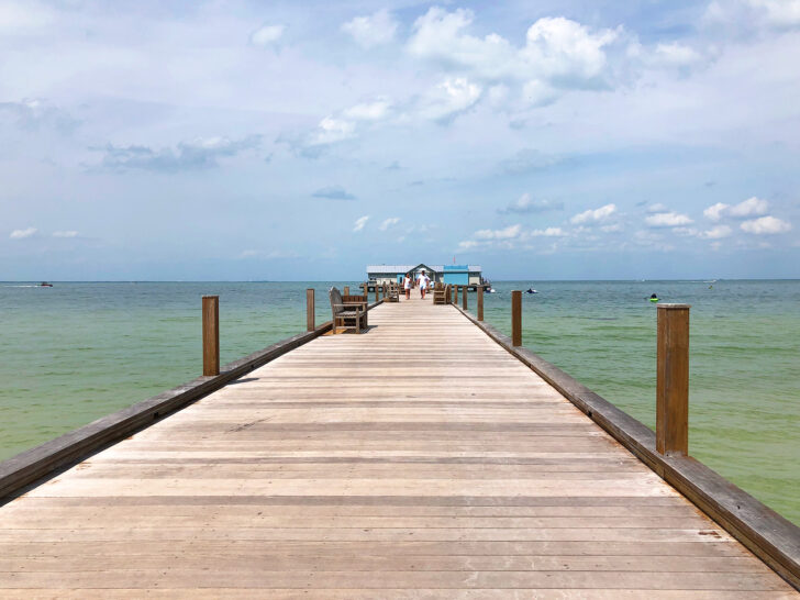 wooden pier with green water and blue cloudy sky