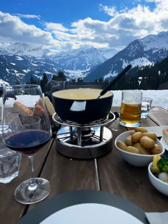 best countries to visit in February  wine and food on table with Swiss alps in distance