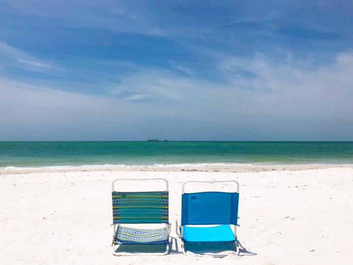two beach chairs set up on white sand with teal water in distance things to do in Anna Maria Island florida
