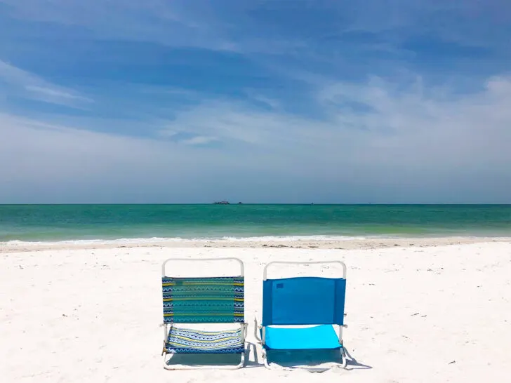 two beach chairs set up on white sand with teal water in distance things to do in Anna Maria Island florida