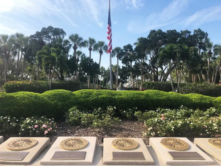 monument with plaques and flag with trees