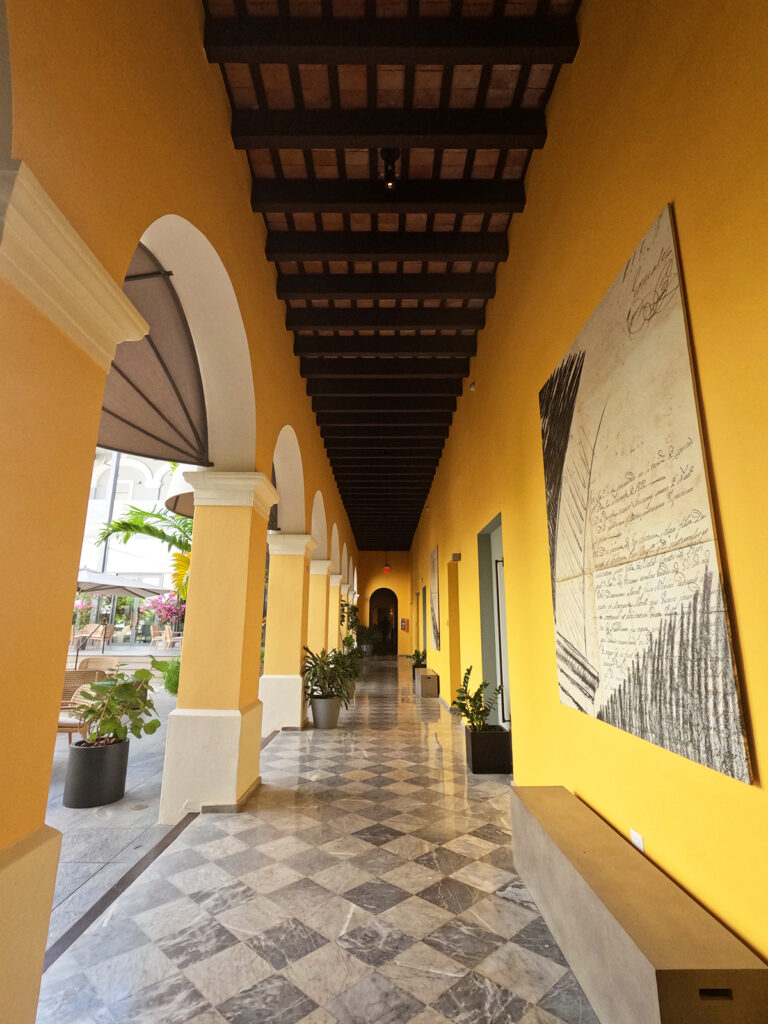 view of yellow hotel hallway with curved architecture and tile