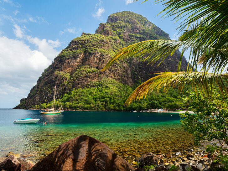 St. Lucia in the caribbean countries to visit in February with views of large mountain and cove with boat in water palm trees