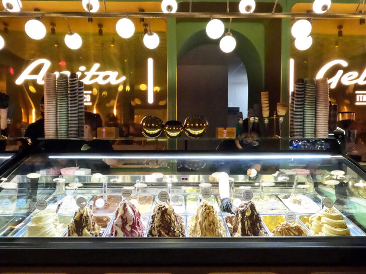 dishing up ice cream in parlor with freezer displaying flavors large lights and mirror wall