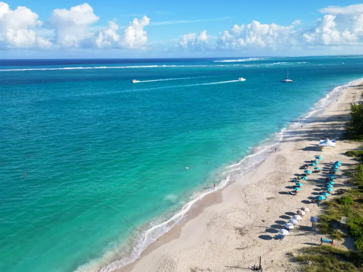 stunning view of Grace Bay Beach best Turks and Caicos beaches with umbrellas teal water and boats