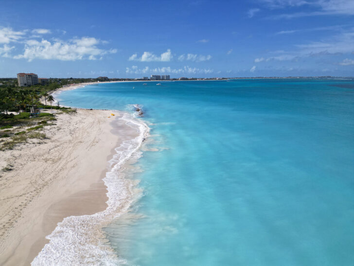 light blue water with white waves and white sand with turks and caicos coastline
