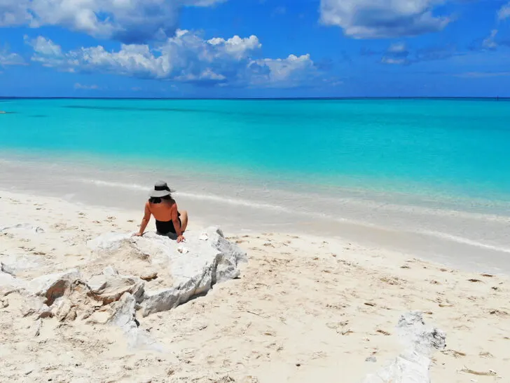 turks and caicos best beaches with woman sitting on rock with teal water in distance