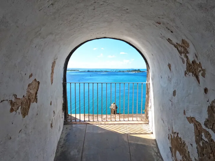 view of the blue ocean through an arch in the fort with old walls in foreground