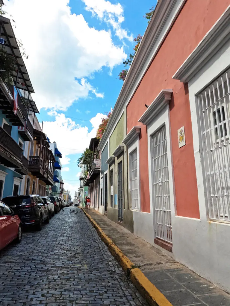 multicolored building with cobblestone streets and car what to see in old San Juan