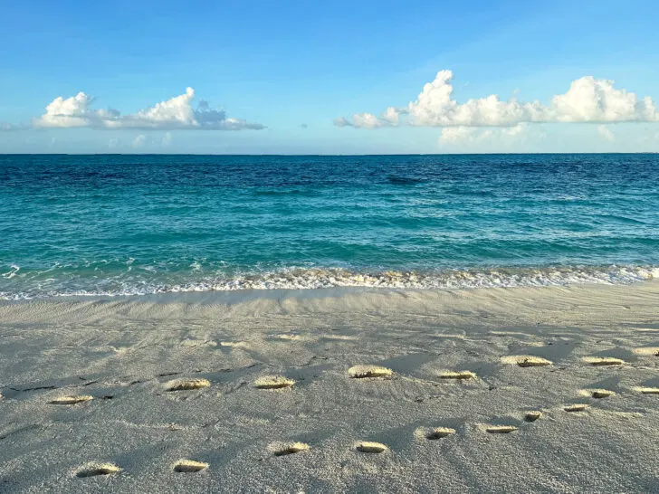 best turks and caicos beaches with view of footprints in sand with blue ocean in distance