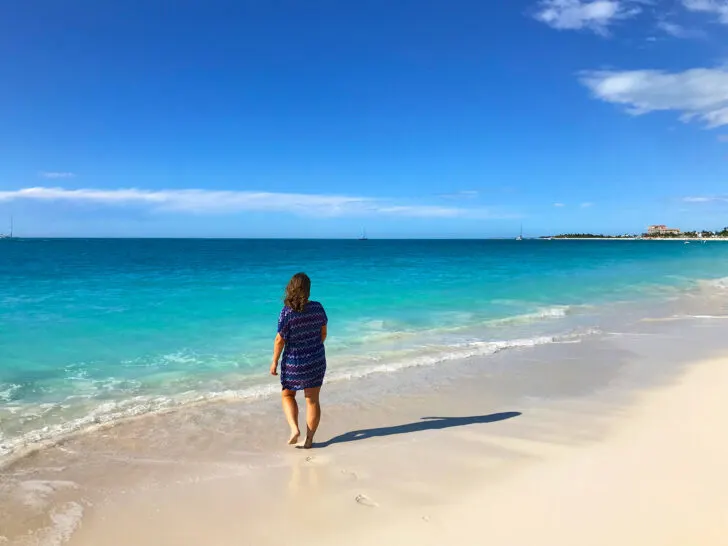 woman walking on grace bay beach with teal water white sand on best Turks and Caicos beaches