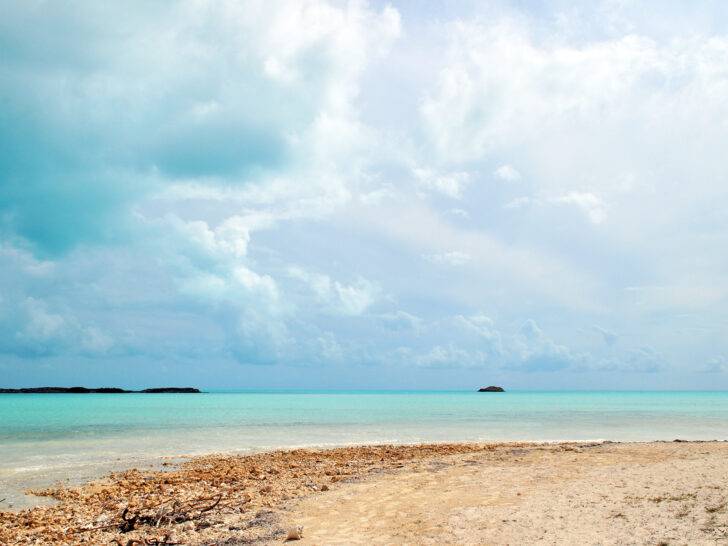Turks and Caicos best beaches view of rocky and sandy beach with teal water cloudy sky and island in the distance