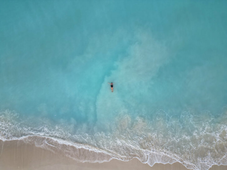 woman floating in water with white beach wave view taken from above best Turks and Caicos beaches