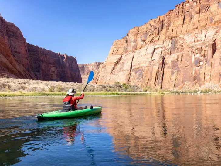 activities in Moab view of woman kayaking the Colorado river in deep canyon