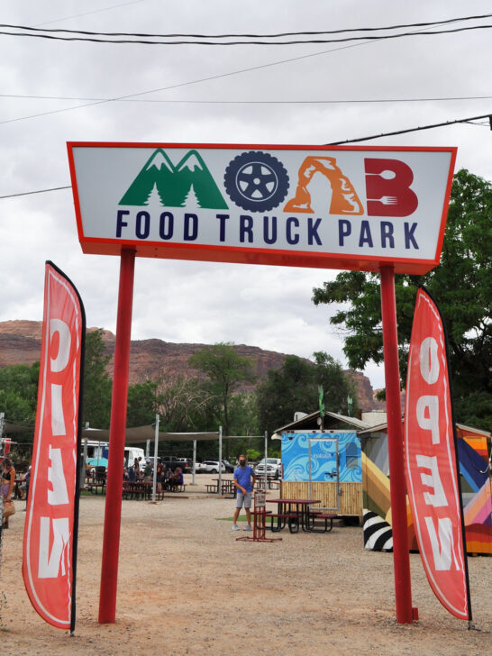 sign that reads moab food truck park with places to eat in distance