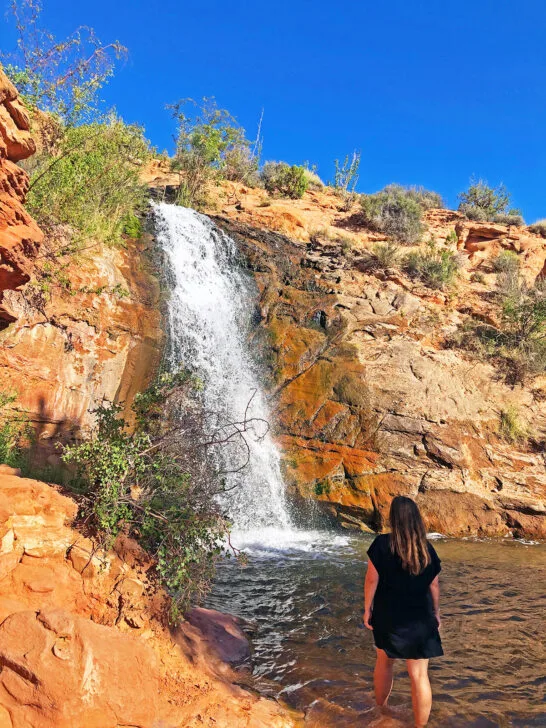 woman in front of waterfall down rocks
