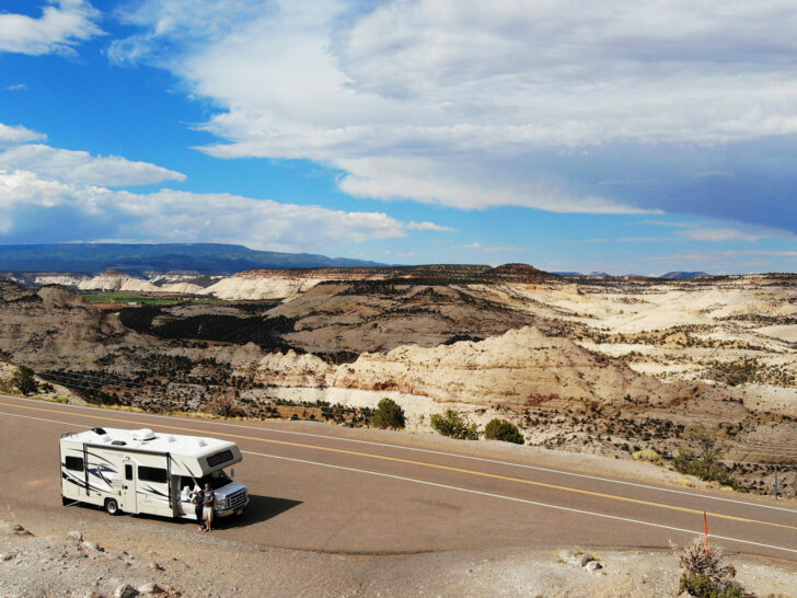couple standing by RV with dramatic Utah landscape behind aerial view