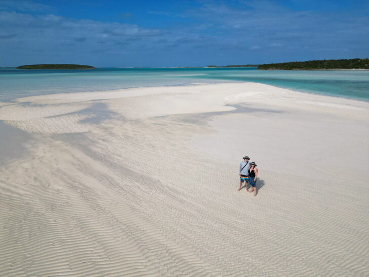 flying a drone in the Bahamas with my husband couple standing on sandbar with water in distance