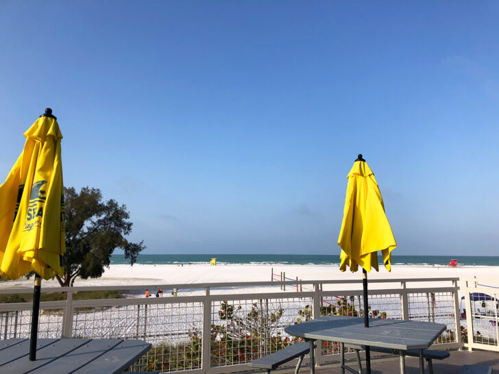 things to do in Siesta Key like eating lunch with a view with two tables yellow umbrellas overlooking Siesta Key Beach