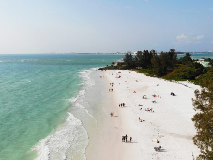 what to see in siesta key beach drone photo of white sand teal water and people on beach