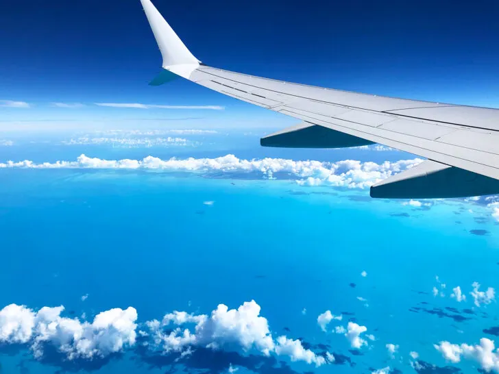 flying with kids with tips and view out window with white puffy clouds airplane wing and bright blue ocean