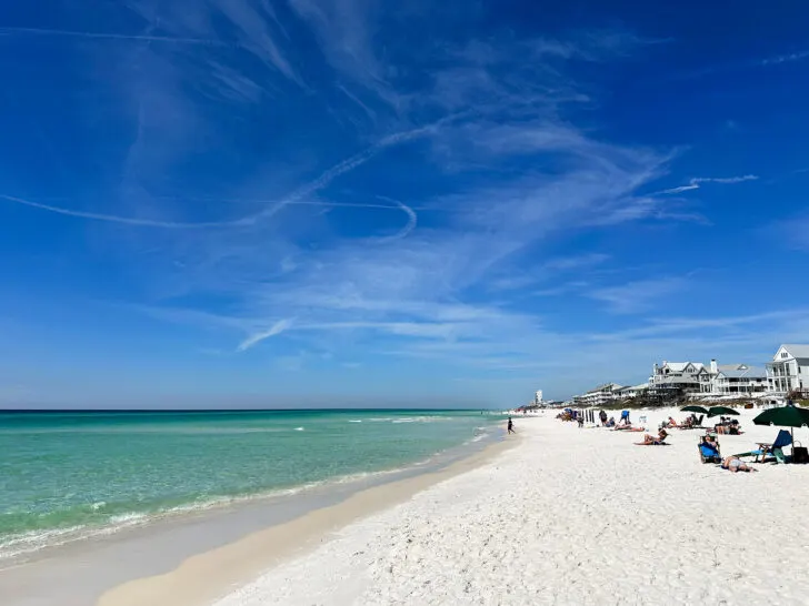 blue sky teal water white sand best 30a beaches with people sitting on beach and houses in distance