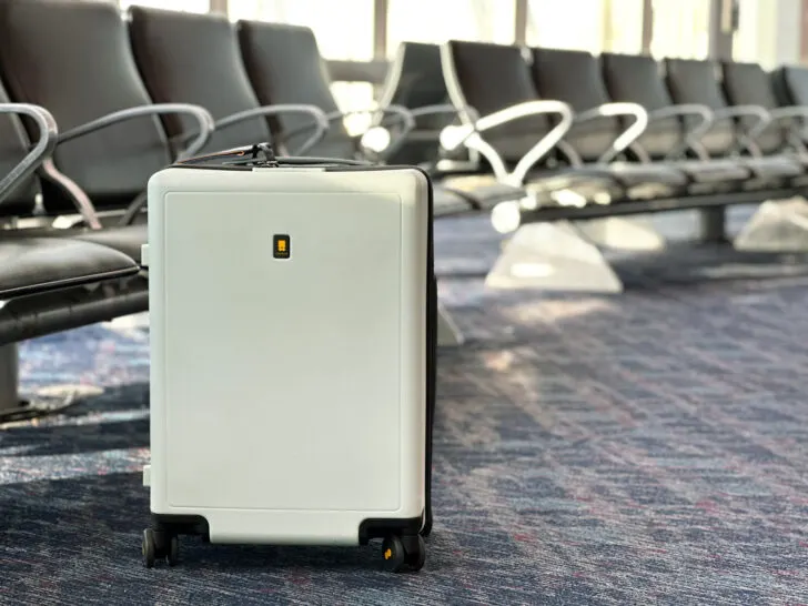 light green suitcase sitting on floor in front of airport chairs