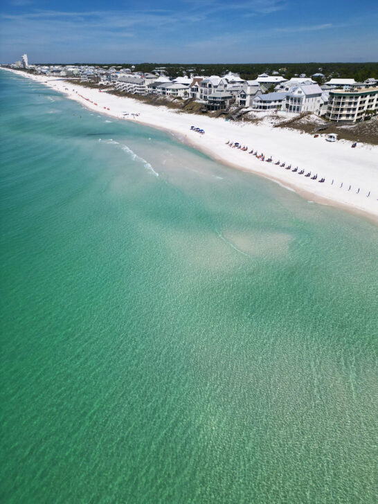 teal water with white sand beach and large houses along coastline 30a florida beaches