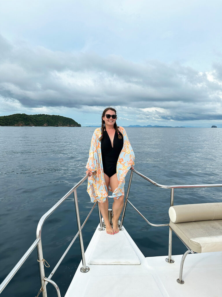 woman in black swimming suit and orange kimono on boat on the ocean