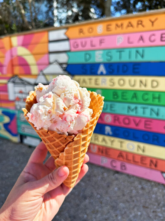 30a FL spring break view of hand holding ice cream cone with colorful mural behind