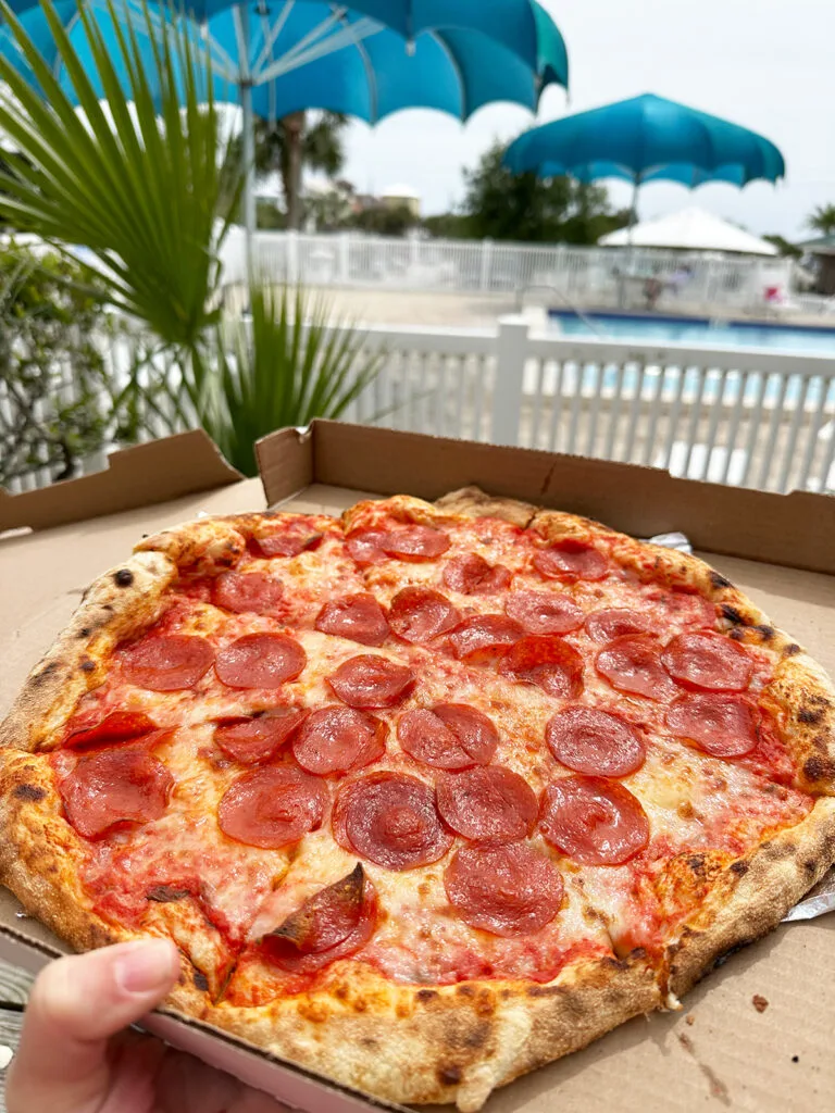 pepperoni pizza in box with pool in distance