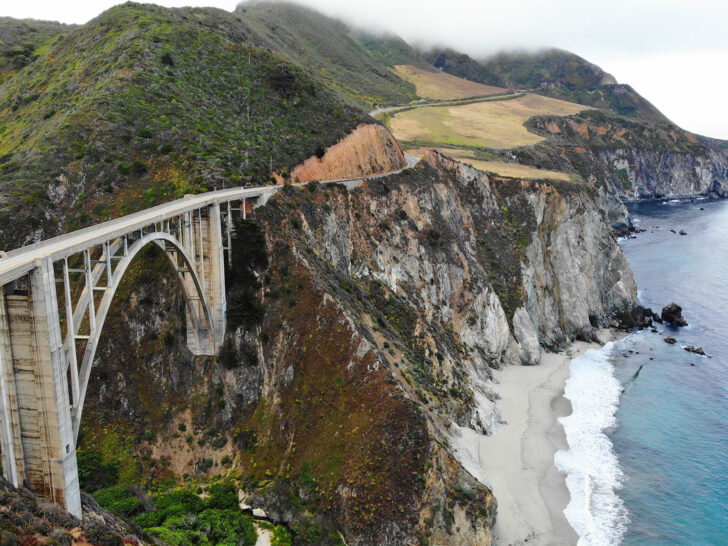 beautiful view of a bridge and coast with fog rolling over hills