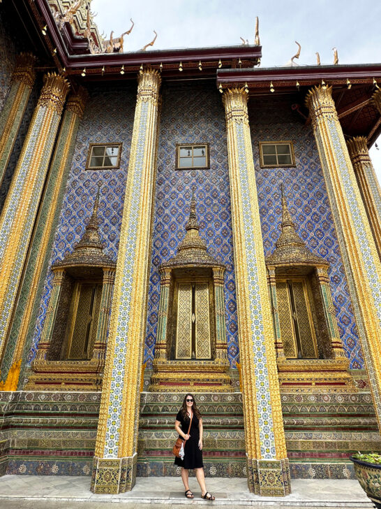 woman in black dress with gold pillars and blue tile at the grand palace