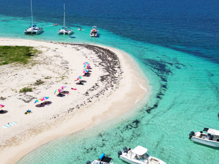 aerial view of island and boats from above with teal and blue water