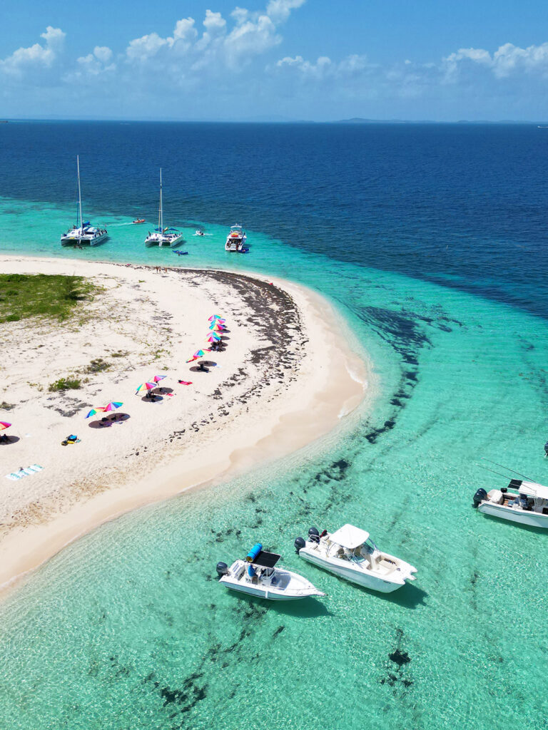 aerial view of island and boats from above with teal and blue water