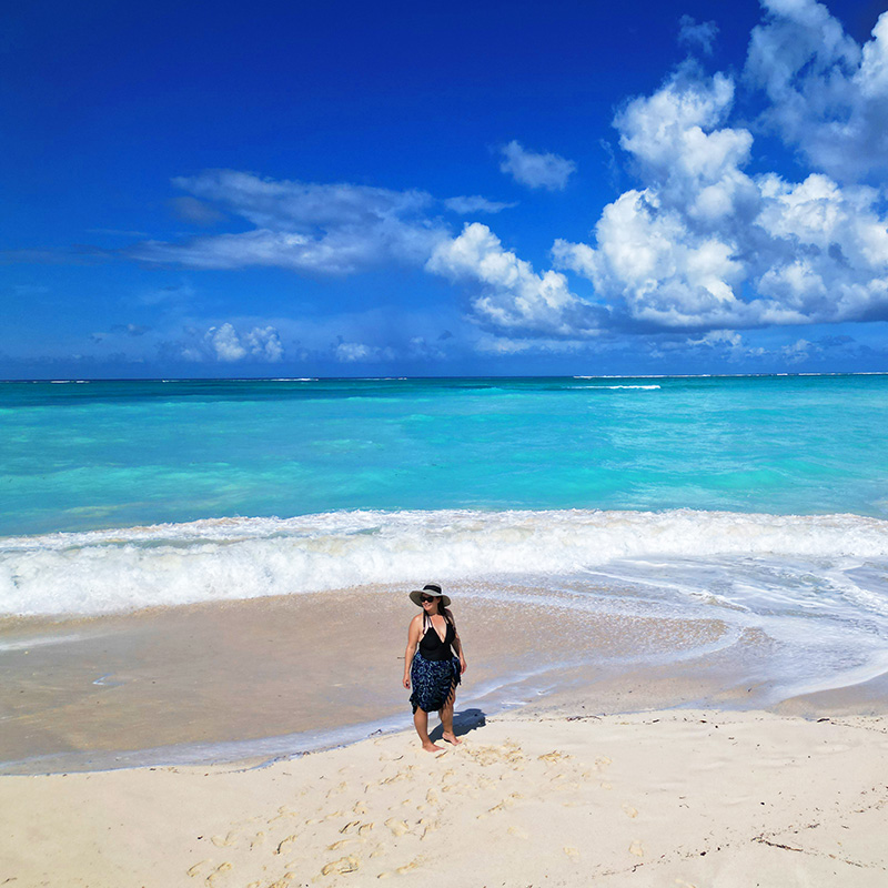 Nikki Rue standing on beach with vibrant water in background