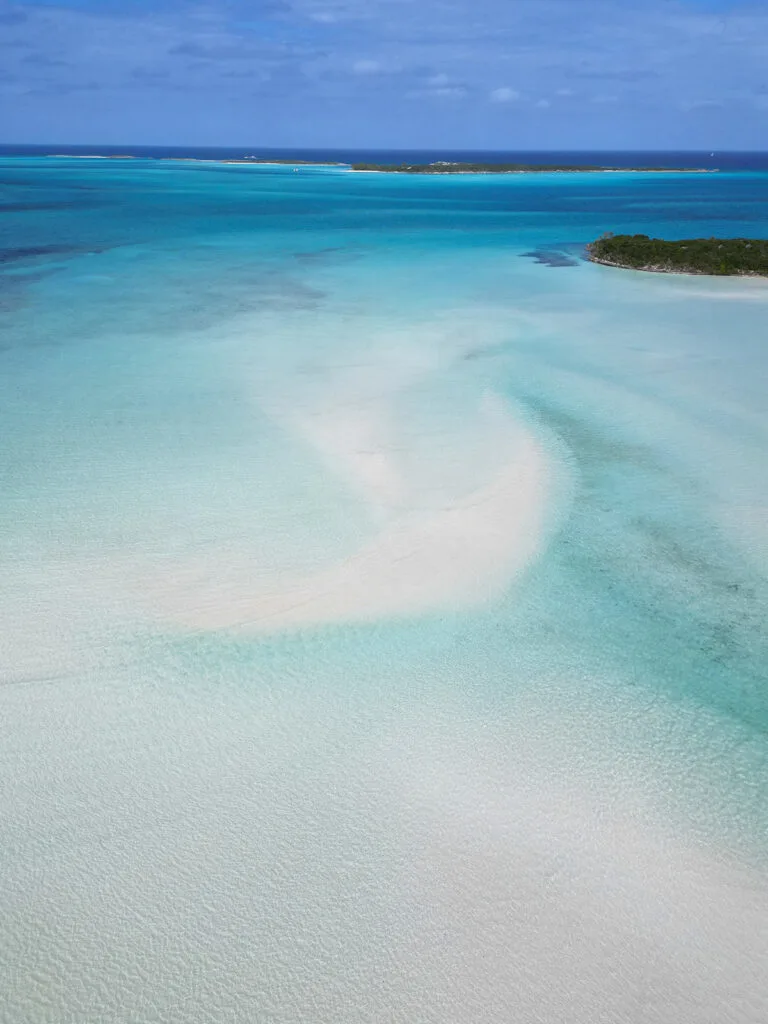 sandbars in ocean with blue water and green lush coastlines