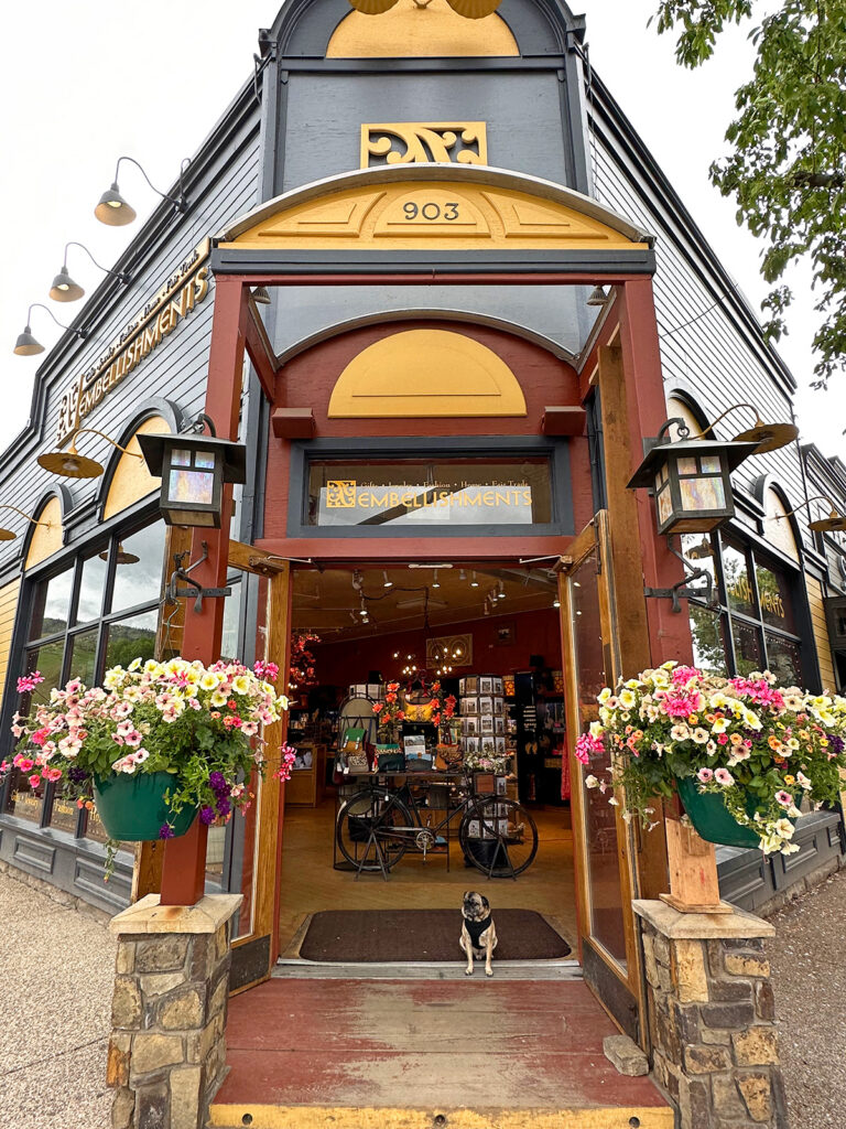 cute shop entrance with flowers gold and brown building and dog sitting in entry way