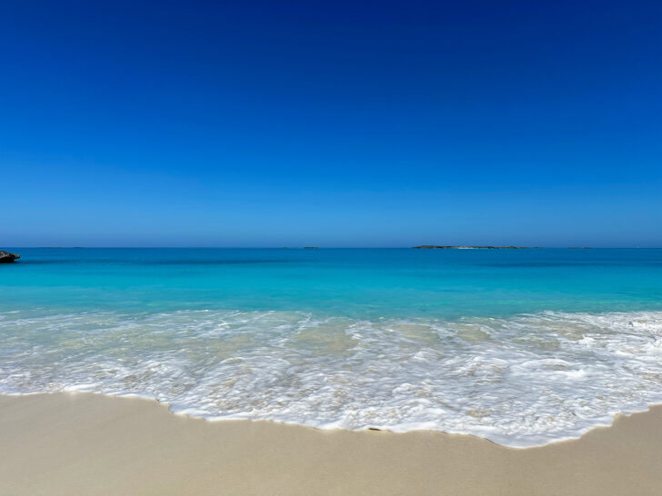 white wave on beach with blue ocean and clear sky