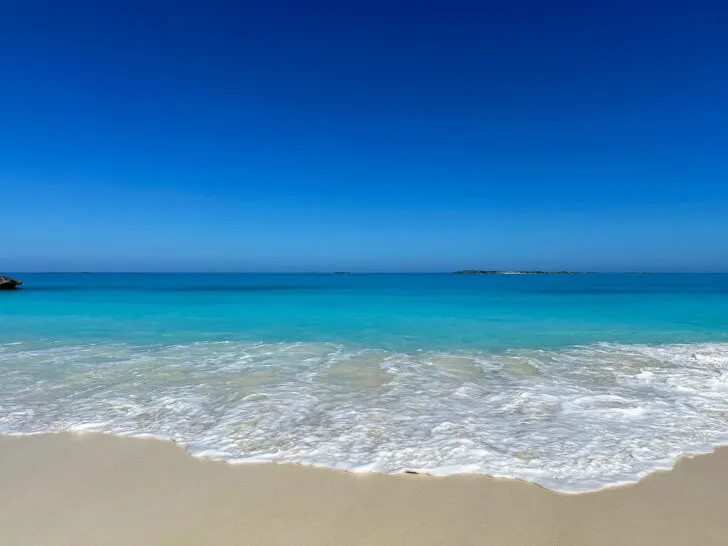 white wave on beach with blue ocean and clear sky