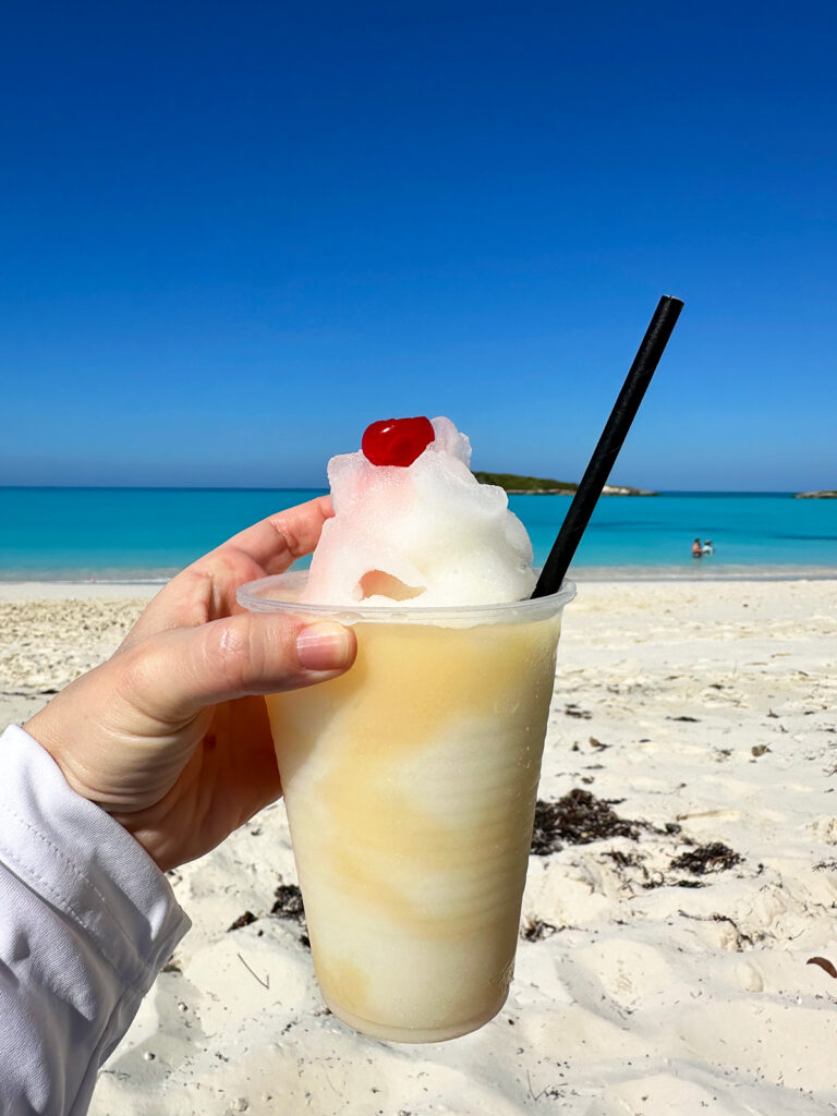 hand holding Pina colada in cup with ocean in background