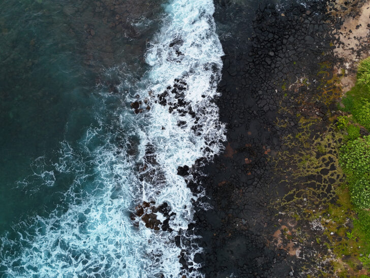 black rock beach at dusk with dark blue and white wave aerial drone photo of kauai hawaii