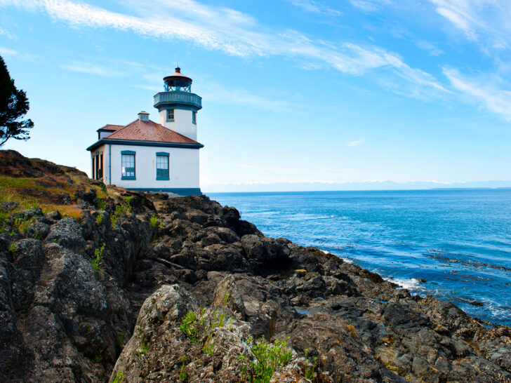 San Juan islands lighthouse on cliff with blue water and mountains in distance