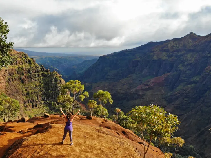 woman standing in canyon holding arms up