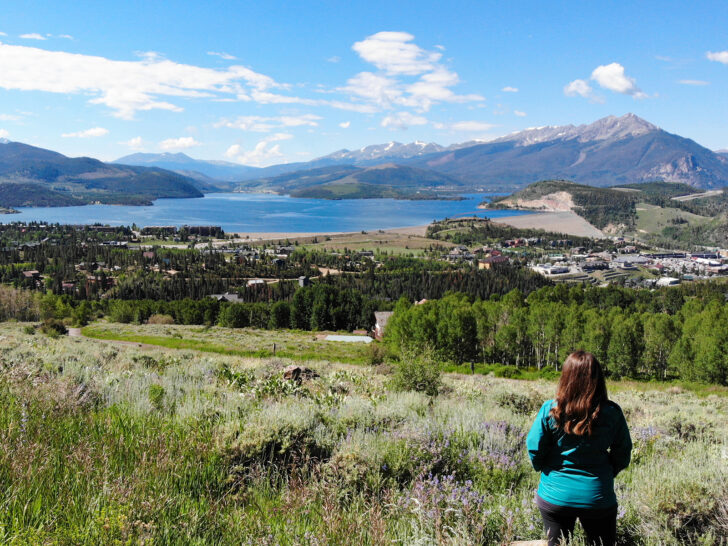 where to fly a drone in Colorado view of woman standing in field with mountain and lake in distance